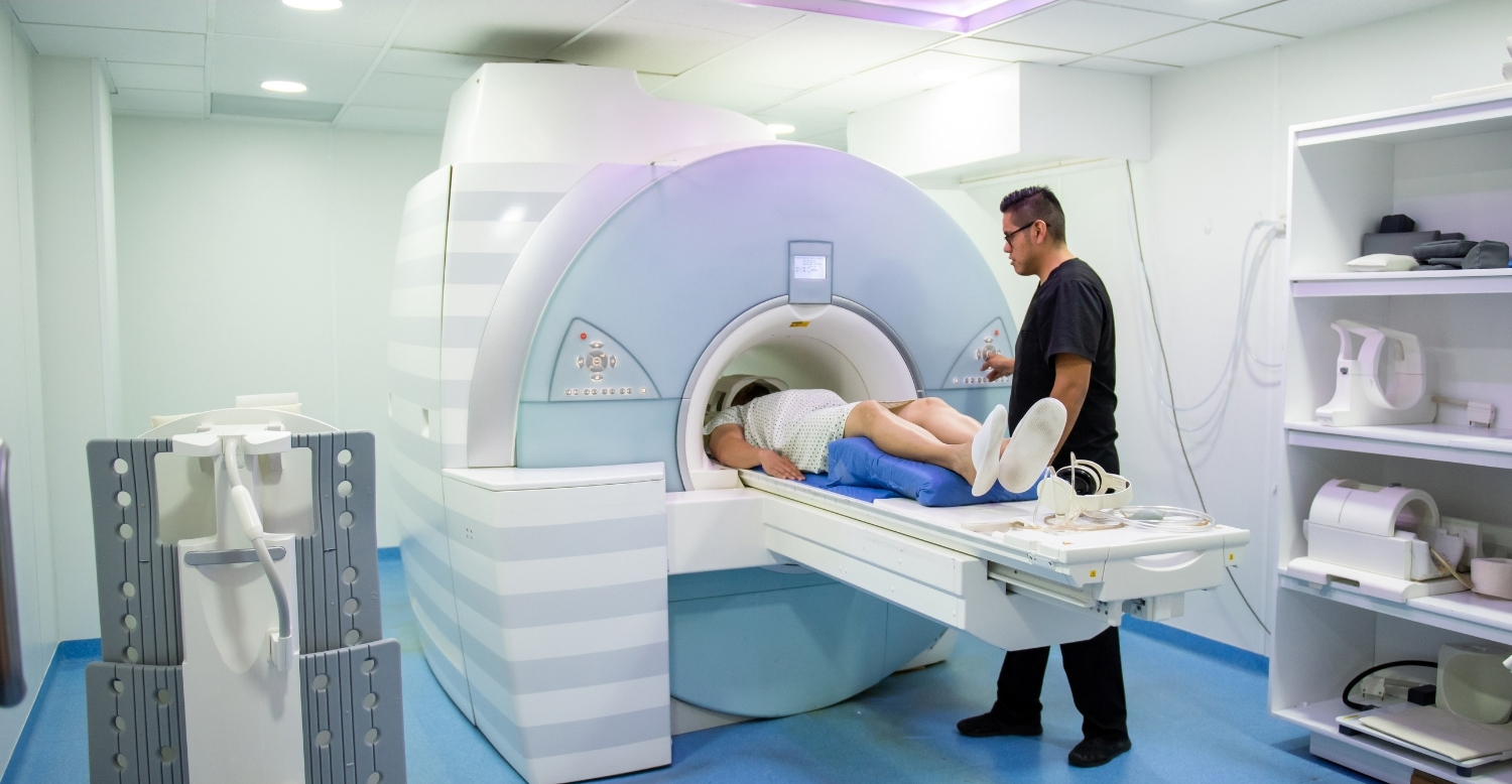 Patient laying on table in front of a positron emission tomography scanner