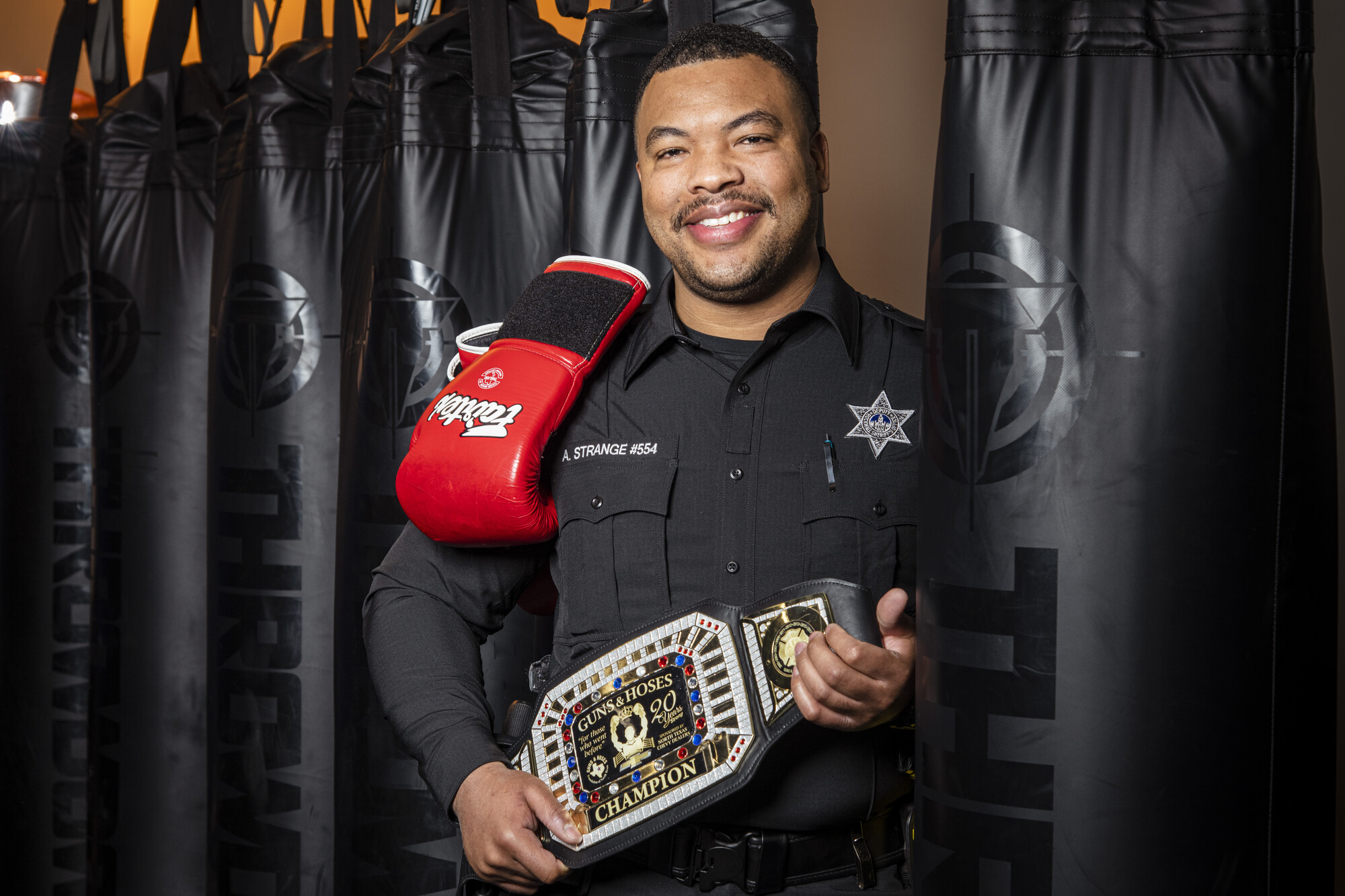 Anthony Strange, Rockwall County deputy sheriff holds Guns and Hoses Police Vs. Fire Boxing belt and gloves