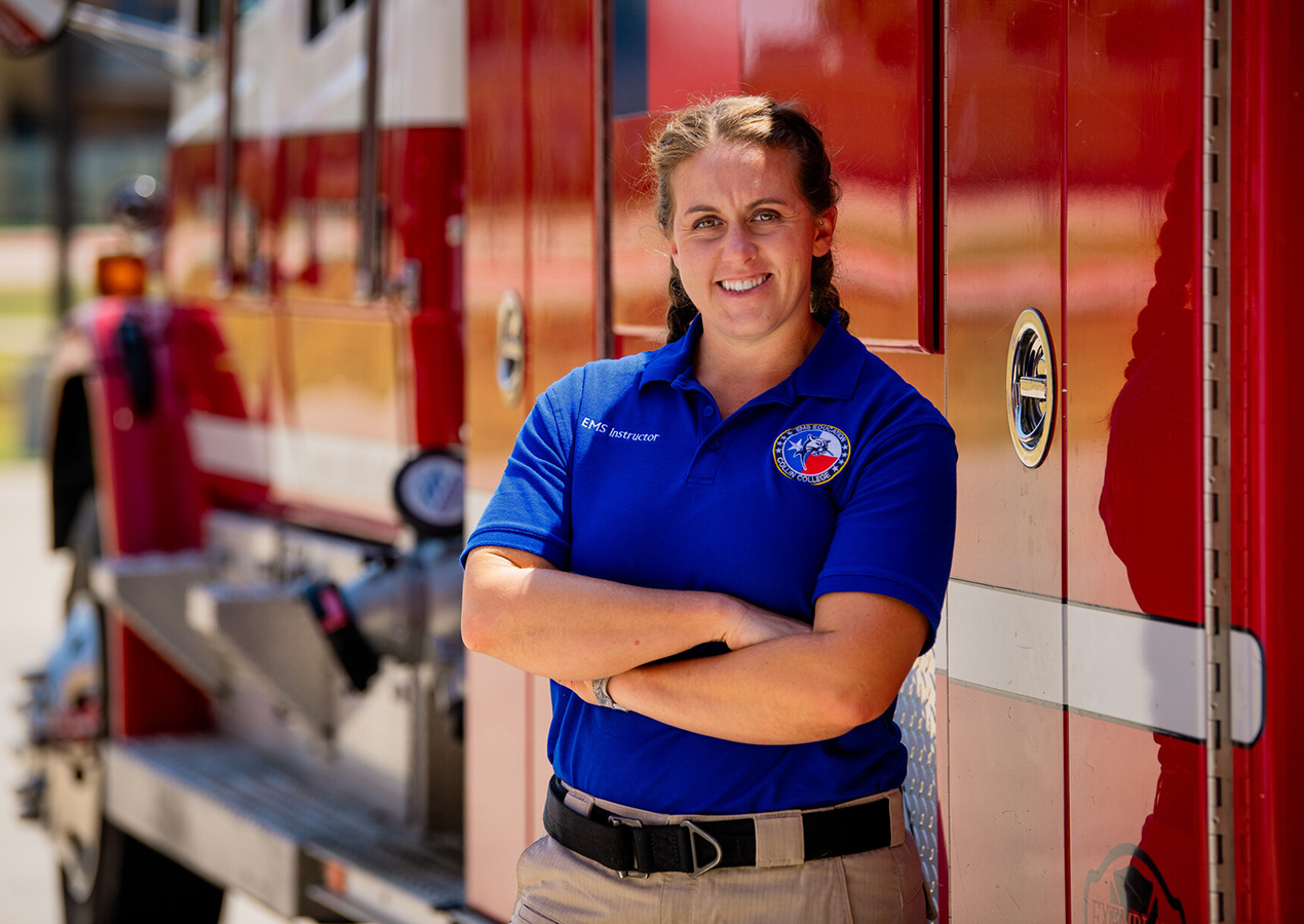 Steph Bouillion, Plano Firefighter and Collin College adjunct faculty stands in front of a fire truck at Collin College's Public Safety Training Center.