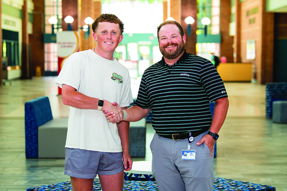 Brodey Deacon (left) shakes hands with Coach Cooper Schoolcraft after signing to play on Collin College’s inaugural golf team. Deacon was the first player to sign with the new team.