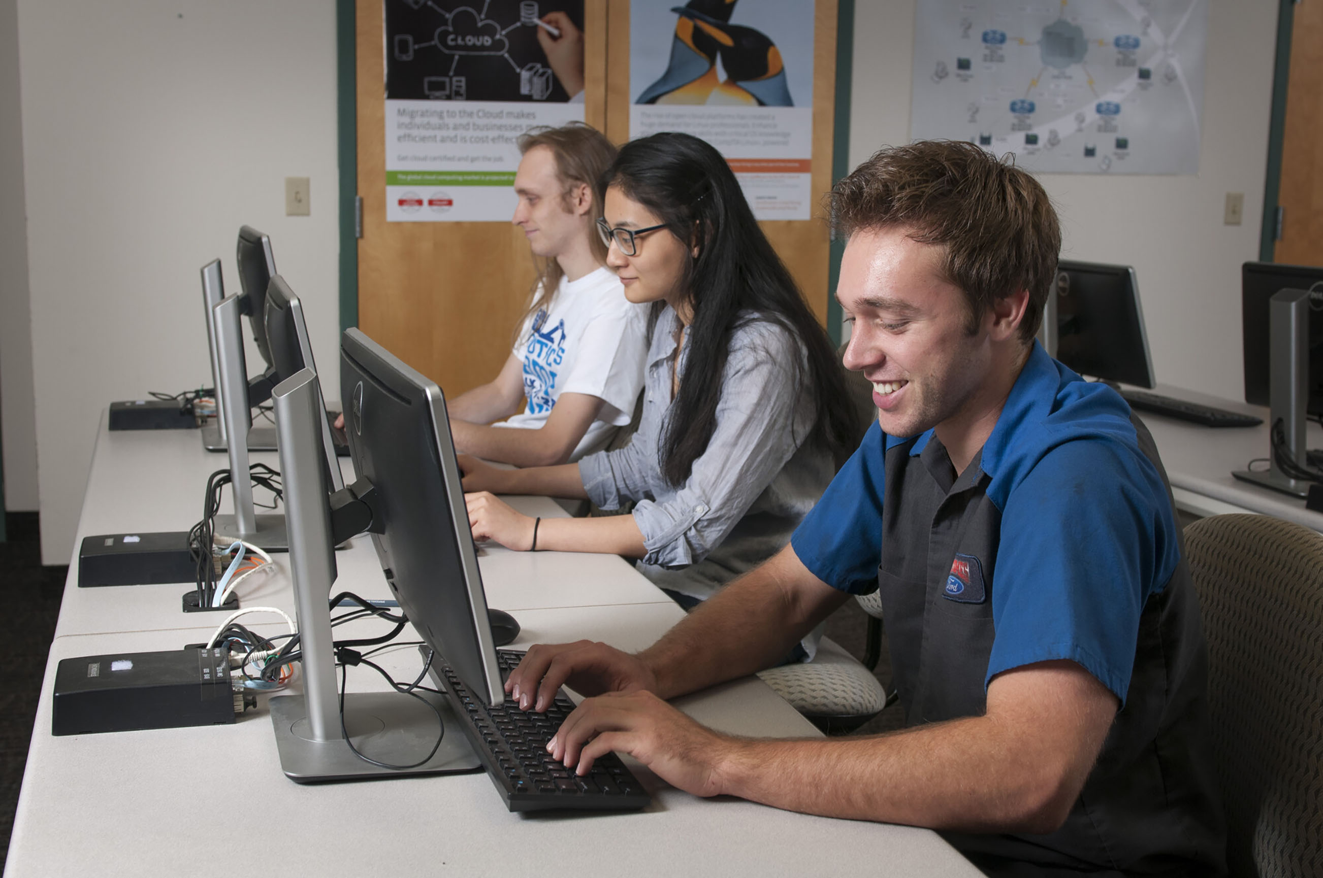 Photo by Nick Young. Three Collin College students type at computer work stations. 