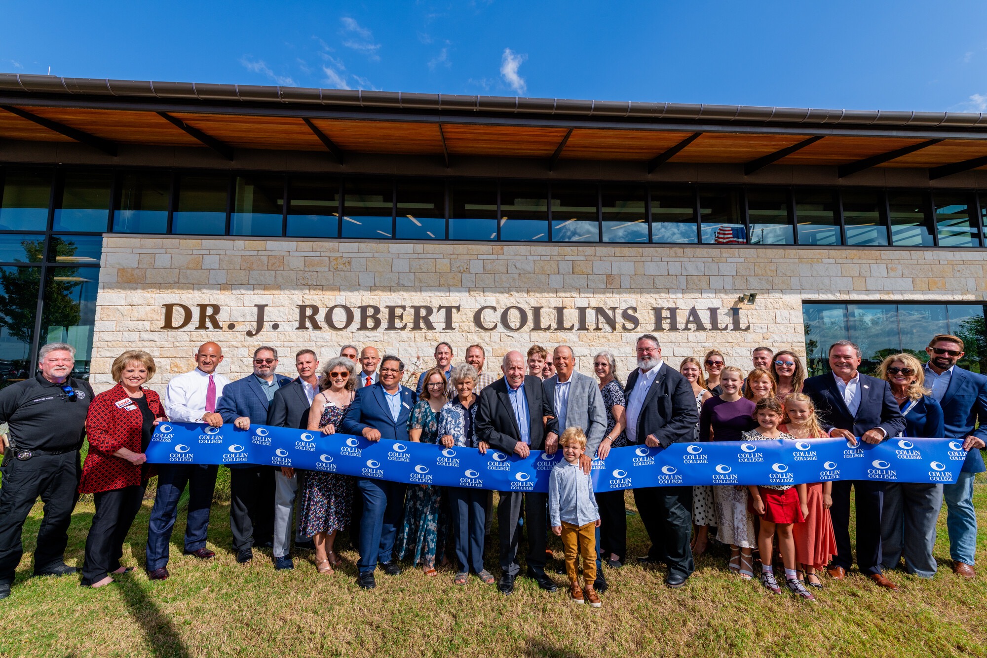 Dr. Collins alongside family members, elected officials, and members of the Collin College Board of Trustees in front of the newly named hall.