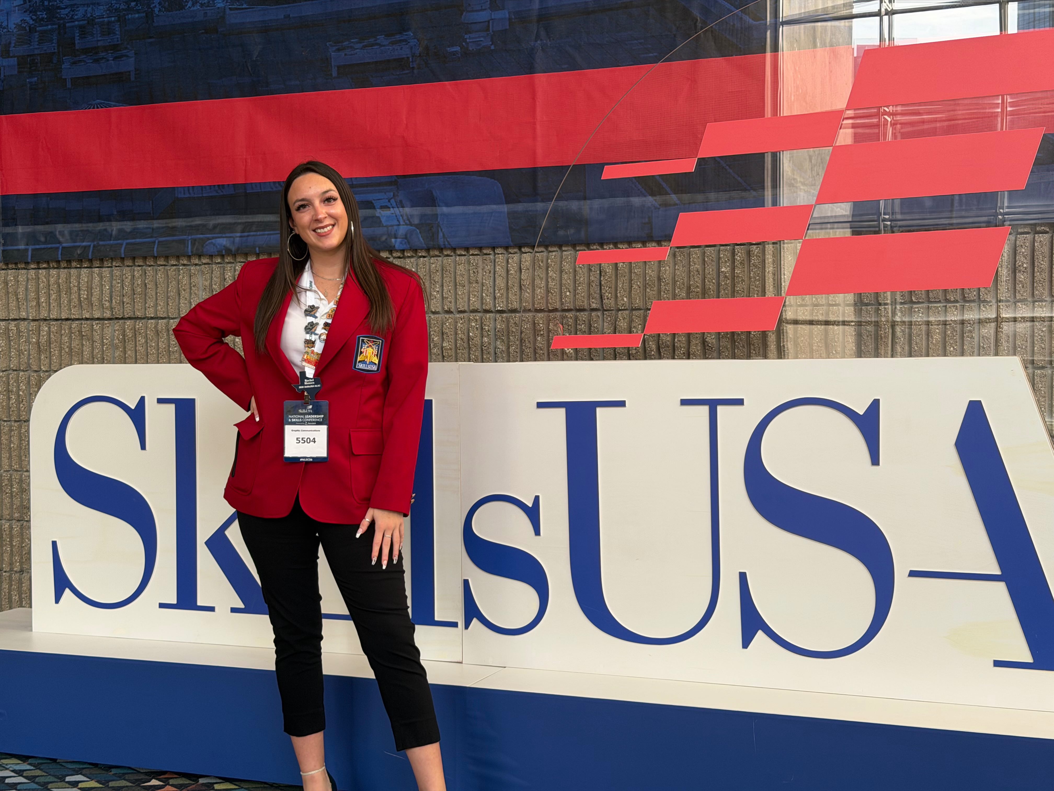 Young woman posing in front of SkillsUSA logo. 