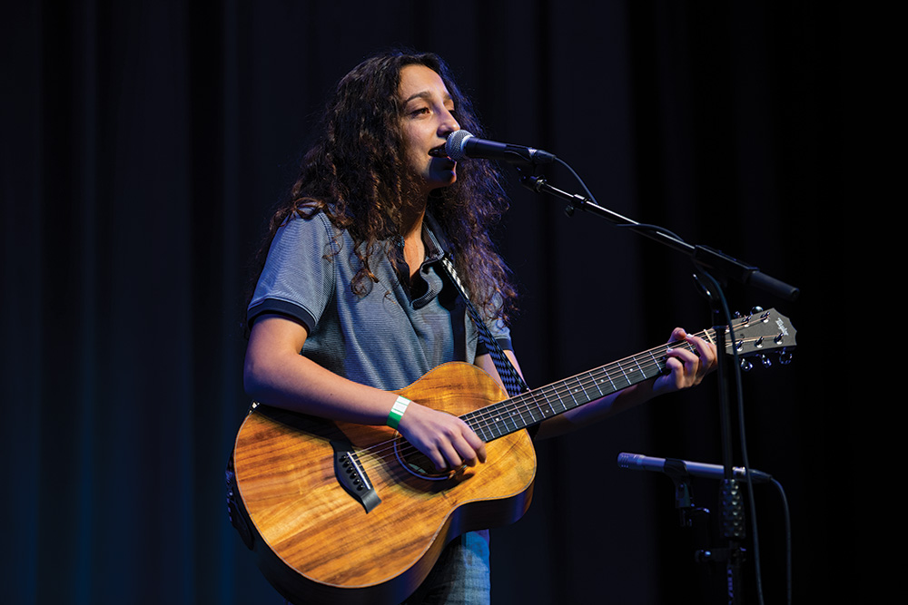 Student preforms on guitar and sings at Collin College event
